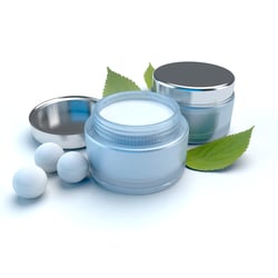Cosmetic cream placed in a jar with leaves in the background