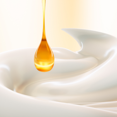 Una goccia di prodotto che cade su una crema cosmetica bianca.