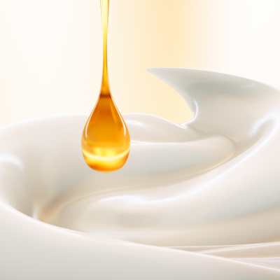 Une goutte de produit qui tombe sur une crème cosmétique blanche.